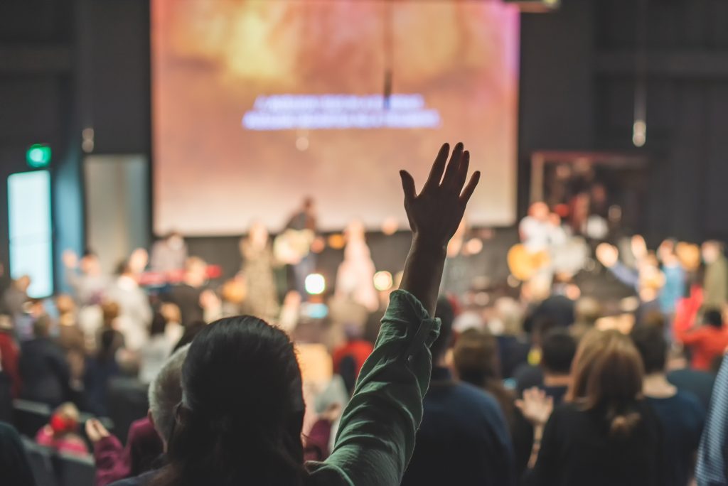 Hands raised in the air in front of a screen at a worship service